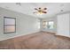 Spacious living room featuring neutral walls, multiple windows, a ceiling fan, and carpeted floors at 6330 W Constance Way, Laveen, AZ 85339