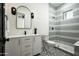 Stylish bathroom with shower, black fixtures, vanity, a rounded mirror, and patterned tile flooring at 7001 E Joan De Arc Ave, Scottsdale, AZ 85254