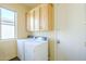 Bright laundry room with a washer, dryer, overhead cabinets, and window at 7438 E Visao Dr, Scottsdale, AZ 85266