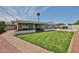 Expansive backyard featuring a pool, manicured lawn, covered patio, and red rock landscaping at 9851 N 28Th Way, Phoenix, AZ 85028