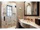 Elegant bathroom features stone tile walls, glass enclosed shower, and a stone countertop with an arched mirror at 1015 W Encanto Blvd, Phoenix, AZ 85007