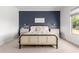 This bedroom features a woven platform bed, soft neutral carpet, and a stylish dark blue accent wall at 1096 E Lodgepole Dr, Gilbert, AZ 85298