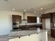 Well-lit kitchen featuring an island, granite countertops, stainless steel appliances, and dark cabinets at 10984 N 164Th Dr, Surprise, AZ 85388