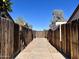 A long walkway between fences offering a glimpse of the clear blue sky above a fenced backyard at 12445 N 21St Ave # 4, Phoenix, AZ 85029