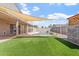 Serene backyard featuring a pristine pool, lush artificial grass, and shade from a custom sunshade at 12745 W Calavar Rd, El Mirage, AZ 85335