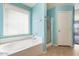 Bright bathroom features a bathtub, separate shower, and a large window for natural light at 12745 W Calavar Rd, El Mirage, AZ 85335