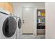 Functional laundry area featuring modern washer and dryer, storage shelves, and convenient access door at 12745 W Calavar Rd, El Mirage, AZ 85335