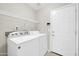 Bright laundry room with modern washer, dryer, and overhead storage shelving at 12938 W Mandalay Ln, El Mirage, AZ 85335