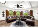 Open-concept living room featuring a leather sectional, arched windows with shutters, and a ceiling fan at 1338 W Mountain View Dr, Mesa, AZ 85201