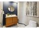 Stylish powder room with a modern vanity, round mirror, and elegant patterned flooring at 14123 W Greentree S Dr, Litchfield Park, AZ 85340