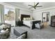 Spacious main bedroom with ceiling fan, seating area, tray ceiling, and serene views at 14123 W Greentree S Dr, Litchfield Park, AZ 85340