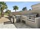 The outdoor kitchen is equipped with stainless steel grills, a fridge, and ample counter space at 14123 W Greentree S Dr, Litchfield Park, AZ 85340