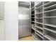 Walk-in pantry with ample shelving and storage space, adjacent to a full-size refrigerator at 14123 W Greentree S Dr, Litchfield Park, AZ 85340