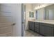 Well-lit bathroom features gray cabinets, double sinks, and a large mirror at 16355 W Desert Mirage Dr, Surprise, AZ 85388