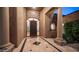 Elegant home entrance featuring a decorative iron door, stone archway, and tiled foyer at 16432 S Mountain Stone Trl, Phoenix, AZ 85048