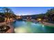 Backyard swimming pool with a waterfall, lush landscaping, surrounding desert vegetation and lounge area at dusk at 16432 S Mountain Stone Trl, Phoenix, AZ 85048