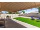 Relaxing backyard with a covered patio, lush artificial turf, and a charming outdoor seating area at 19413 N 8Th St, Phoenix, AZ 85024