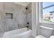 Bathroom with tiled tub/shower combo, matte black fixtures, and window with neighborhood view at 21663 N 57Th Ave, Glendale, AZ 85308