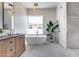 Modern bathroom with freestanding tub, pendant lighting, wood vanity, and large window offering natural light at 21663 N 57Th Ave, Glendale, AZ 85308