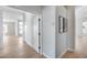 Hallway with light wood floors, showcasing open doorways and natural light at 21663 N 57Th Ave, Glendale, AZ 85308