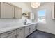 Bright laundry room with gray cabinets, quartz countertops, and black tiled floor at 21663 N 57Th Ave, Glendale, AZ 85308