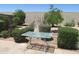 Relaxing backyard with a patio table, stone flooring, lush bushes, and a block fence for privacy at 2324 W Via Rialto Cir, Mesa, AZ 85202