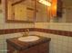 Close-up of the bathroom sink area, highlighting tiled walls, a vintage sink and wooden cabinets at 2324 W Via Rialto Cir, Mesa, AZ 85202