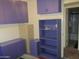 Bedroom with built-in shelves and cabinet, purple walls, and view to bathroom at 2324 W Via Rialto Cir, Mesa, AZ 85202
