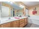 Well-lit bathroom with double sinks, a large mirror, and a separate tub and shower at 23717 N Mustang Way, Florence, AZ 85132