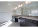 Bathroom featuring dual sinks, granite countertops, dark cabinets and a large mirror at 257 S 165Th Ave, Goodyear, AZ 85338