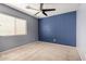 Bedroom with a ceiling fan, large window, carpeted floor, and blue accent wall at 2718 S Cupertino Dr, Gilbert, AZ 85295
