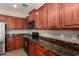 View of kitchen stove with wooden cabinets and granite countertop and tile flooring at 2718 S Cupertino Dr, Gilbert, AZ 85295