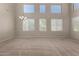 Expansive living room features large windows offering natural light, neutral carpet and modern chandelier at 2718 S Cupertino Dr, Gilbert, AZ 85295