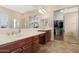 Bright primary bathroom featuring double sinks, large mirror, and a walk-in closet with sliding mirrored doors at 2856 E Desert Broom Pl, Chandler, AZ 85286
