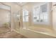 Modern bathroom featuring a glass enclosed shower, a soaking tub, and a large window with plantation shutters at 2856 E Desert Broom Pl, Chandler, AZ 85286