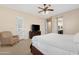 A cozy bedroom showcases a ceiling fan, a comfortable armchair, and a dresser with a modern television at 2856 E Desert Broom Pl, Chandler, AZ 85286