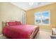 Bedroom with large window, tan walls, a red bedspread, and a white ceiling fan at 2856 E Desert Broom Pl, Chandler, AZ 85286