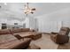 Spacious living room features a large brown leather sectional couch, a ceiling fan and adjacent kitchen at 2856 E Desert Broom Pl, Chandler, AZ 85286