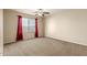 Bright bedroom featuring neutral walls, carpeting, a ceiling fan, and a large window with red curtains at 30617 N 138Th Way, Scottsdale, AZ 85262