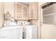 Functional laundry room with upper cabinets and white washer and dryer units for efficient chores at 325 E Sharon Ave, Phoenix, AZ 85022