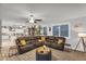Open-concept living room featuring a large sectional couch, wood-look tile flooring, and plenty of natural light from the windows at 3445 E Pageant Pl, Gilbert, AZ 85297