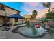 Backyard pool area featuring a rock waterfall, outdoor lighting, and lounge areas perfect for entertaining guests at 3445 E Pageant Pl, Gilbert, AZ 85297