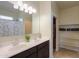 Bright bathroom boasts a double sink vanity with a large mirror, open shelving, and decorative accents at 36522 W Santa Monica Ave, Maricopa, AZ 85138