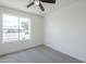 This bedroom offers gray carpet, neutral walls, ceiling fan, and a window overlooking the front yard at 3722 W Michelle Dr, Glendale, AZ 85308