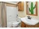 Well-lit bathroom featuring a tiled shower-tub combo, vanity and a decorative cactus mirror at 3836 W Desert Cove Ave, Phoenix, AZ 85029