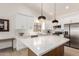 Stylish kitchen features white cabinetry, stainless steel appliances, and a spacious island with marble countertops at 3971 N 151St Ln, Goodyear, AZ 85395
