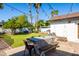 Lush backyard with a dining table, seating, string lights, mature trees and a swing set in the background at 4418 E Paradise Ln, Phoenix, AZ 85032