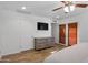 Bedroom with wood-look floors, dresser, TV, and doors leading to outdoor space at 4418 E Paradise Ln, Phoenix, AZ 85032