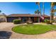 Charming single-story brick home featuring a manicured lawn, gravel landscaping, and mature palm trees under a bright blue sky at 4418 E Paradise Ln, Phoenix, AZ 85032