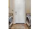 Bright laundry room featuring a white door, stainless steel washer and dryer, and wood-look flooring at 4418 E Paradise Ln, Phoenix, AZ 85032